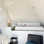 Schlafzimmer mit Hochbett, Nachttisch und Stuhl unter schrägen Dachschrägen.