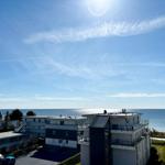 Meerblick von einer Wohnung mit modernen Gebäuden und klarem Himmel.