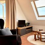 Wohnzimmer mit Sessel, TV und Dachfenster. Holztisch und Teppich auf Terrakottboden.