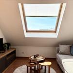 Dachgeschosswohnung mit Dachfenster, Sofa und Holztisch.