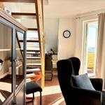Wohnraum mit Sitzgelegenheit, Glasvitrine und Treppe zur oberen Etage.