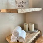Holzregal mit Handtüchern und Keramikbechern. Schild mit Schriftzug büschen pustig.