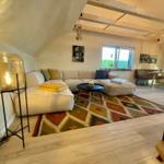 Wohnzimmer mit Sofa, Teppich und Lampe. Holzboden und Balken an der Decke.