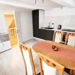 Essbereich mit Holztisch und Stühlen. Küche mit Arbeitsplatte und Geräten. Tür führt in einen Flur.
