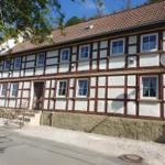Fachwerkhaus mit Steinsockel und Dachgauben. Satellitenschüssel an der Fassade.
