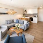 Wohnzimmer mit Sofa, Couchtisch und Küchenbereich mit weißen Schränken.