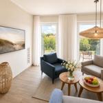 Wohnzimmer mit Sitzgelegenheiten, TV und Balkonansicht.