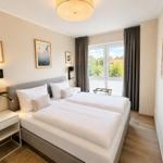Schlafzimmer mit Doppelbett, Fenster und Wandbildern.