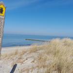 Nationalpark-Schild an Strand mit Dünen und Meer