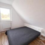 Schlafzimmer mit Dachschräge, Bett, Fenster und Nachttisch.