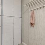Wand mit Holzoptik, Kleiderständer und weißer Schrankwand mit Lüftungsschlitzen.