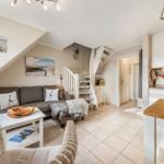 Living area with sofa, table, and kitchen. Staircase to upper level.