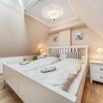 Bedroom with double bed, nightstands, and wicker chair under sloped ceiling.