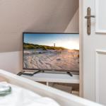 TV on desk next to door with beach image