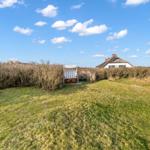 Green lawn area with beach chair and view of house with roof