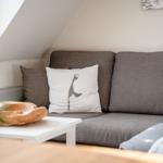 Gray sofa with cushions under sloped ceiling