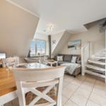 Dining area with table, chairs, and view of living area with sofa and staircase.