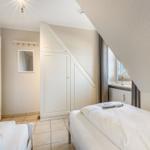 Bedroom with sloped ceiling, white bed, and wardrobe.