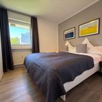 Schlafzimmer mit Bett, Fenster und Wandbildern.