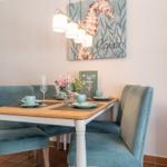 Esszimmer mit Tisch, Stühlen und Wandbild mit Seepferdchen.