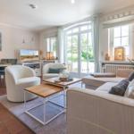 Wohn- und Essbereich mit Sofa, Stühlen und TV. Große Fenster und Terrasse.