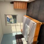 Schlafzimmer mit Bett, Fenster und Holzschränken