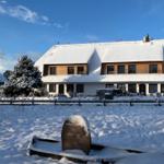 Snow-covered house with wooden windows and snow-covered ground.