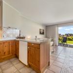 Kitchen with wooden cabinets and view of terrace with garden.