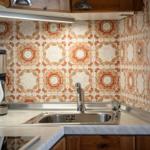 Kitchenette with mosaic backsplash, sink, and appliances.