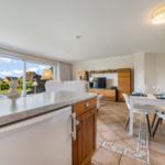 Kitchen-living area with dining table, TV, and garden view.