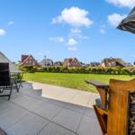 Terrace with garden view of traditional houses and green lawns under blue sky.