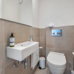 Bathroom with sink, toilet, and mirror on the wall.