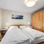Bedroom with double bed, wooden wardrobe, and nightstands.