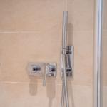 Showerhead with wall-mounted shower and handheld shower on beige tiled wall