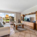 Living room with sofa, TV, and view of garden