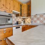 Kitchen with wooden cabinets, marble countertop, and mosaic tiles on the wall.