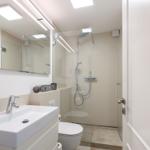 Badezimmer mit Dusche, Waschbecken und Toilette. Moderne Einrichtung mit Spiegel und Beleuchtung.