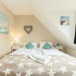 Schlafzimmer mit Dachschrägen, Bett mit Sternen-Decke und Wandbildern.