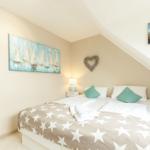 Schlafzimmer mit Dachschrägen, Bett mit Sternen-Decke, zwei Nachttische und Wandbild mit Segelbooten.