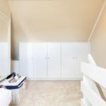 Schlafzimmer mit weißem Schrank, Spiegel und Wandbild mit Hirsch.