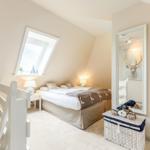 Schlafzimmer mit Dachschräge, Dachfenster, Bett, Spiegel und Korb.