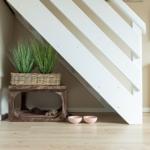Unter der Treppe steht ein Holzstuhl mit Pflanzen und zwei rosa Schalen.