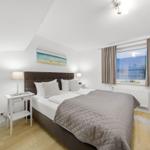 Bedroom with bed, nightstand, and window view of beach.