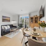 Living and dining area with sofa, table, and TV. Entrance to terrace.