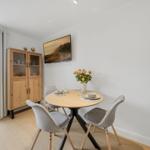 Round table with four chairs, wooden cabinet, and window view.