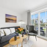Living room with sofa, armchair, and view of terrace.