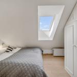 Schlafzimmer mit Dachschrägen, Dachfenster und weißem Schrank.