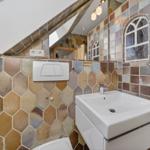 Badezimmer mit farbigen Sechseckfliesen, Waschbecken und Spiegel