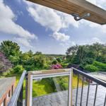 Terrasse mit Blick auf grüne Bäume und einen blauen Himmel mit weißen Wolken.