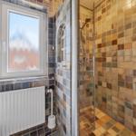 Bad mit Dusche, Fenster und Heizkörper an Wand